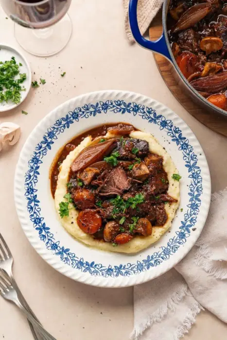 Boeuf Bourguignon upplagt på en tallrik med blåa mönster. Grytan serveras med potatismos.
